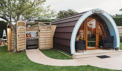 Glamping pod with hot tub beside enclosed with open gate