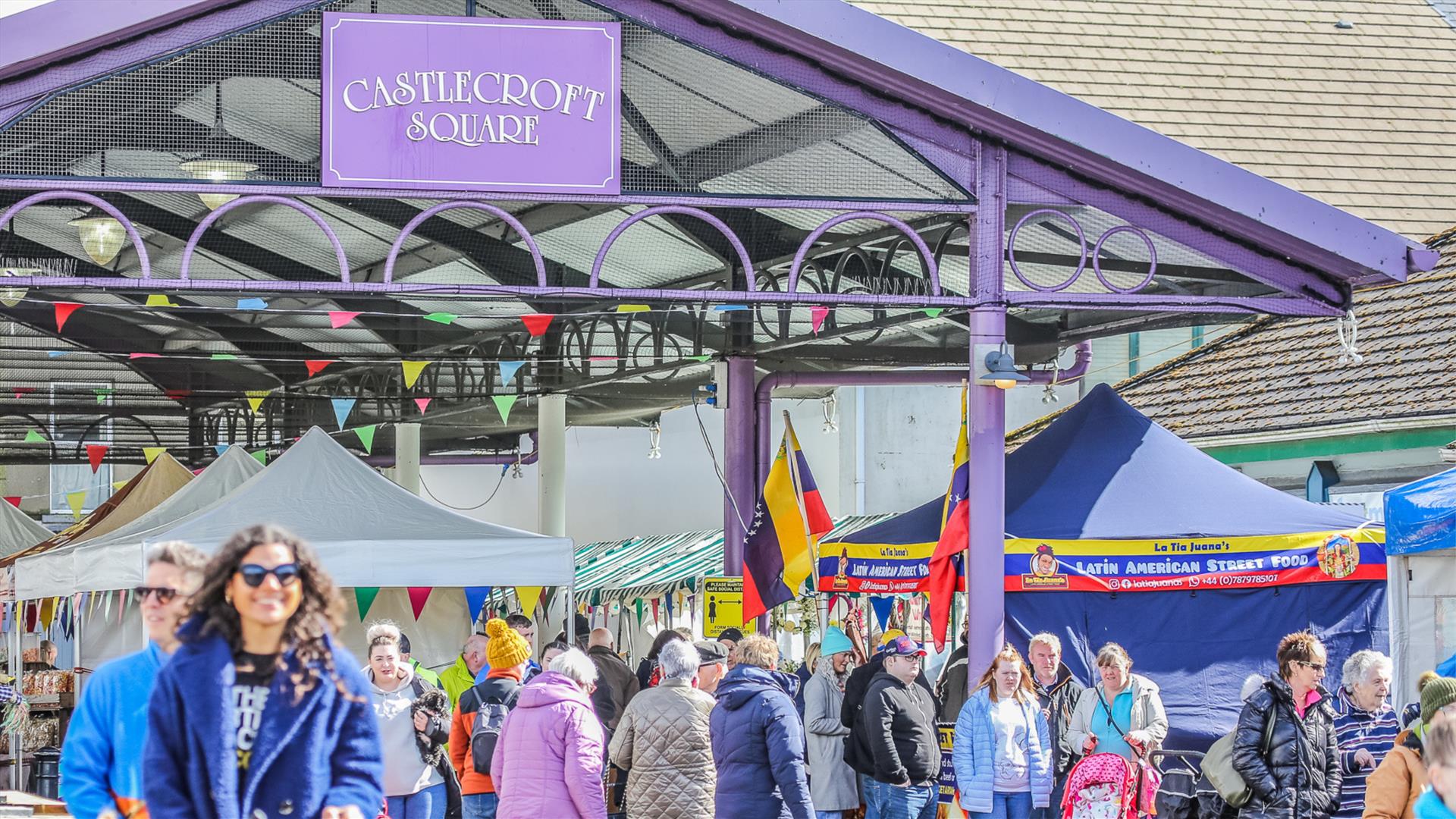 people walking through a market square with stalls people walking through a market square with stalls