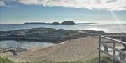 View from front of Ballintoy Beach Cottage of the beach, sea, Sheep Island and Rathlin island with the sun glistening on the water.