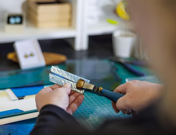 a glass artist uses a cutting tool as part of the fused glass-making workshop