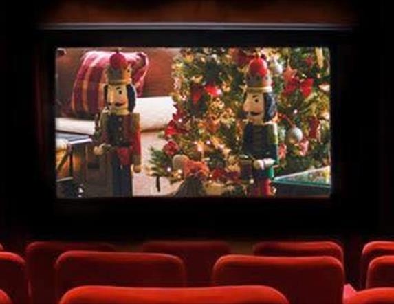 Red chairs in the cinema with a Christmas scene playing on the screen (two nutcrackers and a Christmas tree)