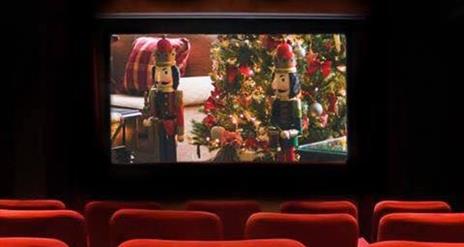 Red chairs in the cinema with a Christmas scene playing on the screen (two nutcrackers and a Christmas tree)