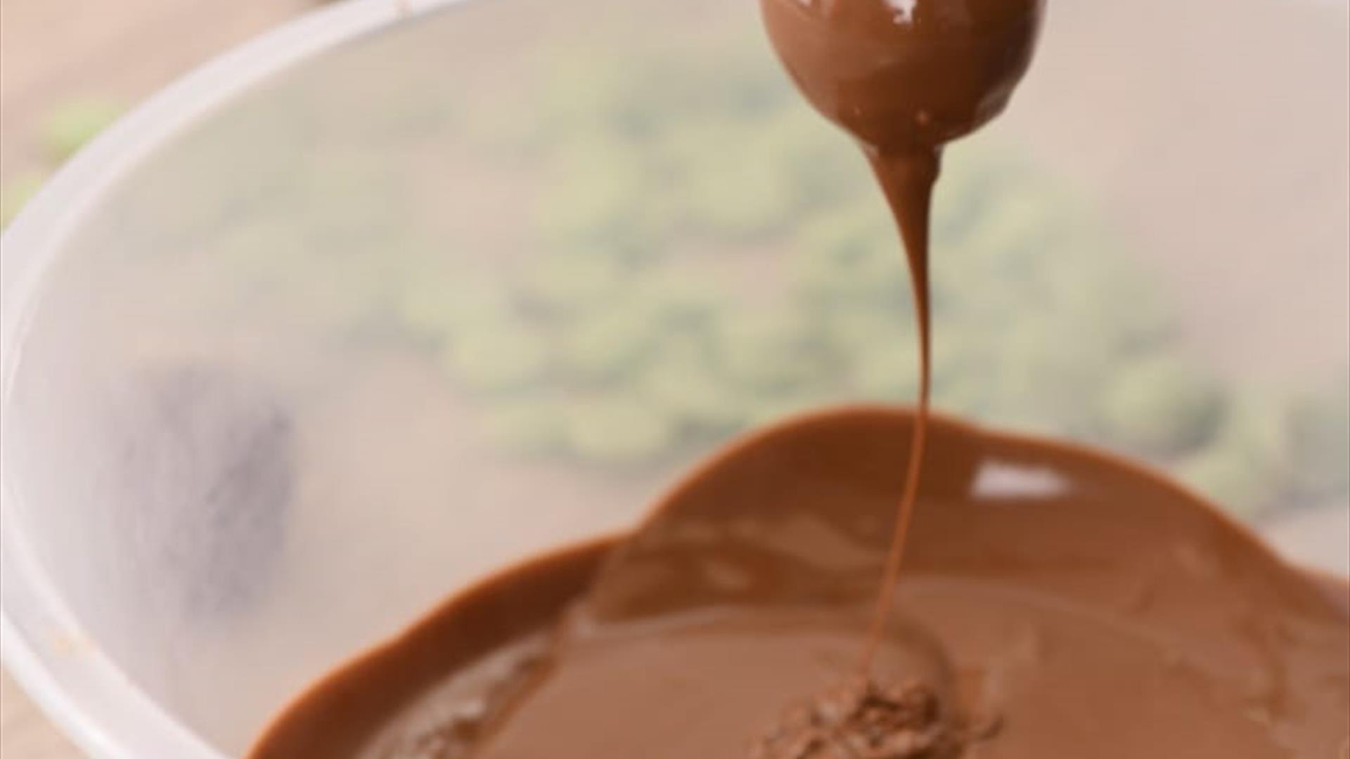 Dipping a handmade truffle in a bowl of melted chocolate