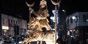 A lady on a white wooden hobby horse passes the crowd as part of the Christmas Cavalcade parade