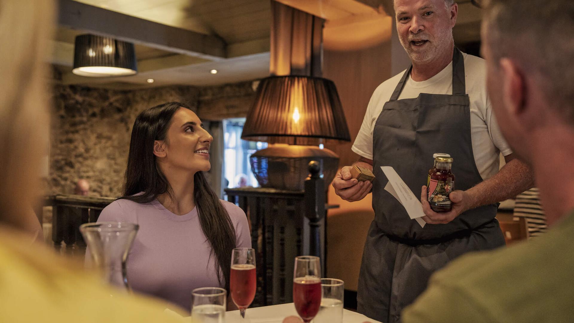 a chef talks to a tour group whilst holding a jar of locally made produce a chef talks to a tour group whilst holding a jar of locally made produce