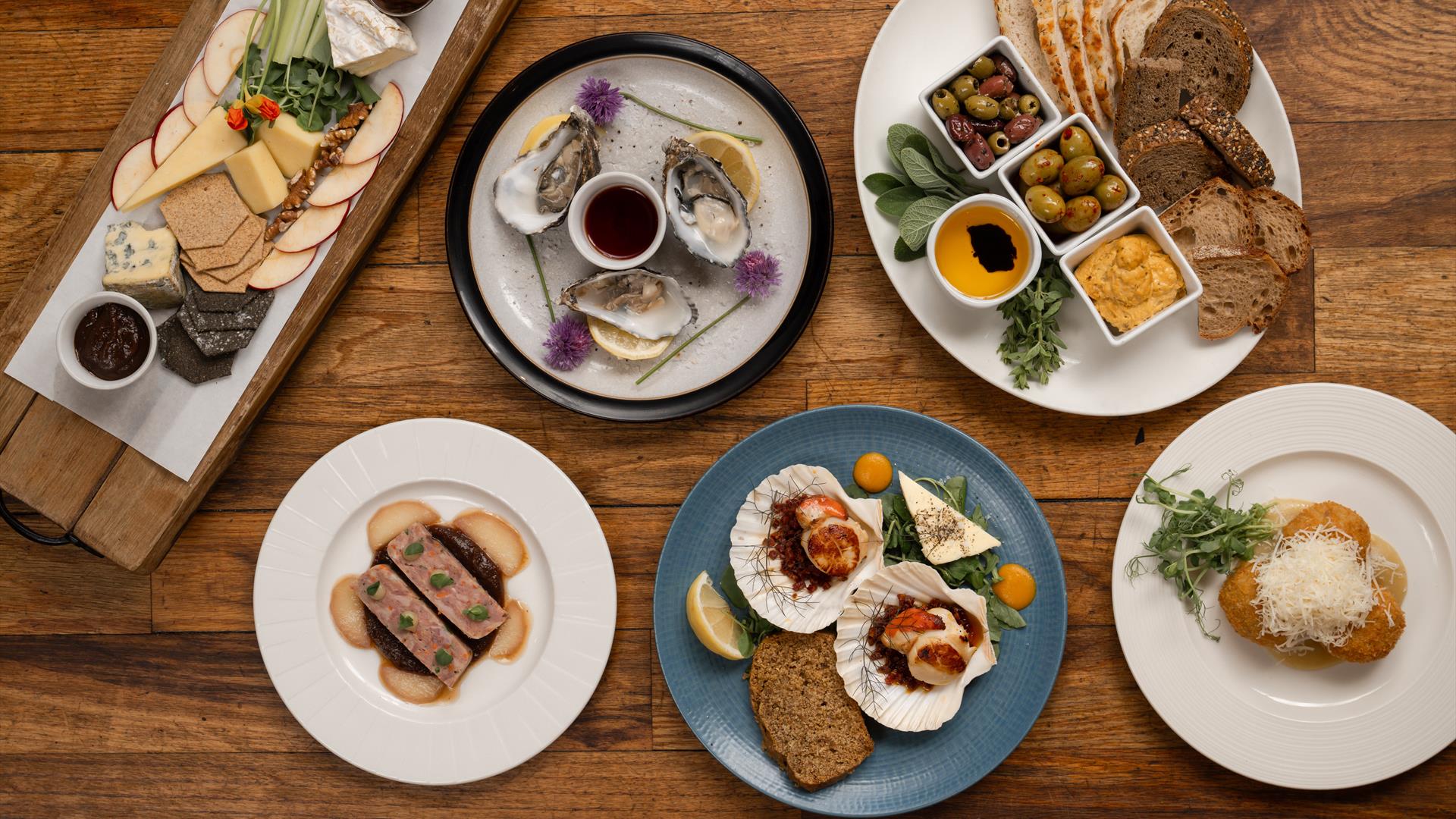 various plates of food sit on a wooden table at Tartine at Distiller's Arms, Bushmills. Some of the dishes include a cheeseboard with various cheeses various plates of food sit on a wooden table at Tartine at Distiller's Arms, Bushmills. Some of the dishes include a cheeseboard with various cheeses