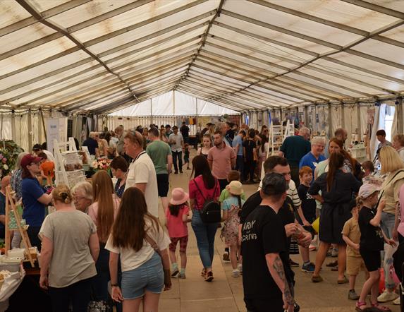 crowds browsing through an indoor market with various stalls at the Ballymoney Show