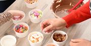 Reaching for toppings during a family experience at The Chocolate Manor
