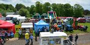 Aerial view of the show, featuring an ice cream van, bouncy castles, bouncy slides,  a blue tractor and people  enjoying the show