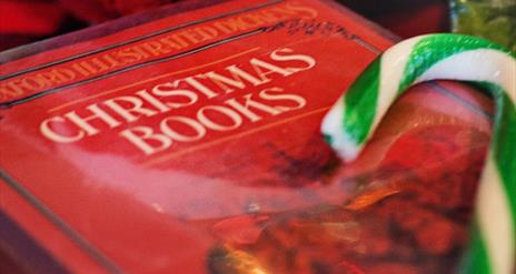 Red book with the words Christmas Books written on the front in white. A green and white candy cane sits off to the side of the book.