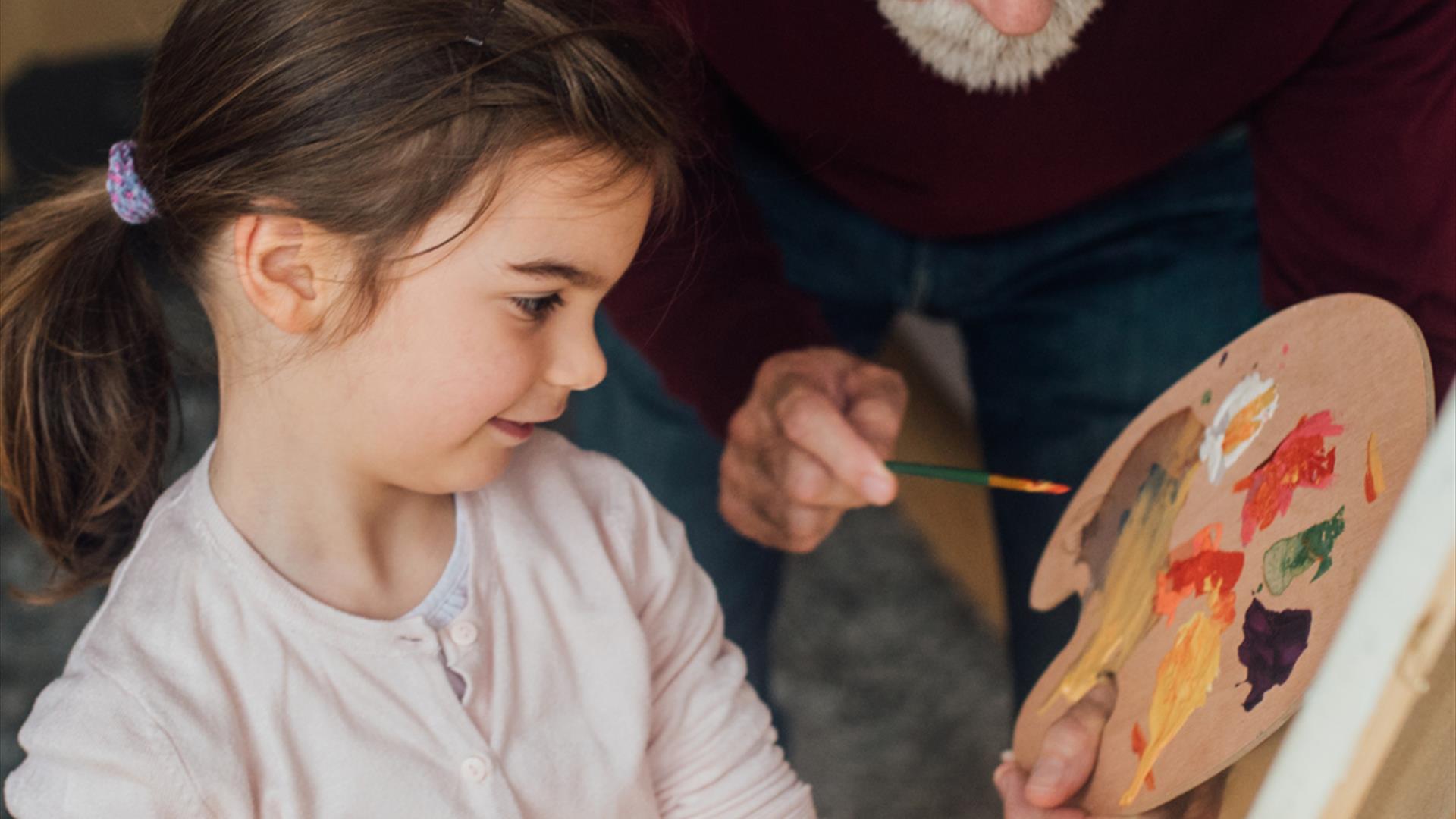 older person and a young child painting happily together. older person and a young child painting happily together.