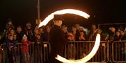 Image shows a man with fire poi entertaining the crowd