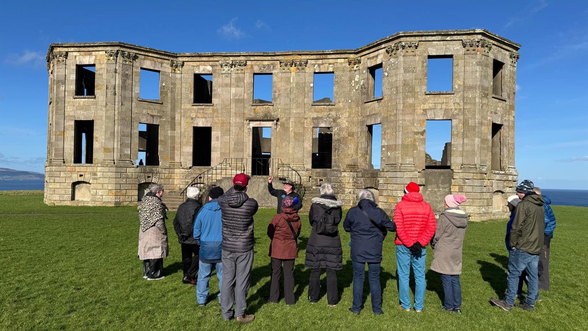 Bob Picken guiding a group in outdoor clothing while looking at the ruins on the Downhill Demesne Bob Picken guiding a group in outdoor clothing while looking at the ruins on the Downhill Demesne