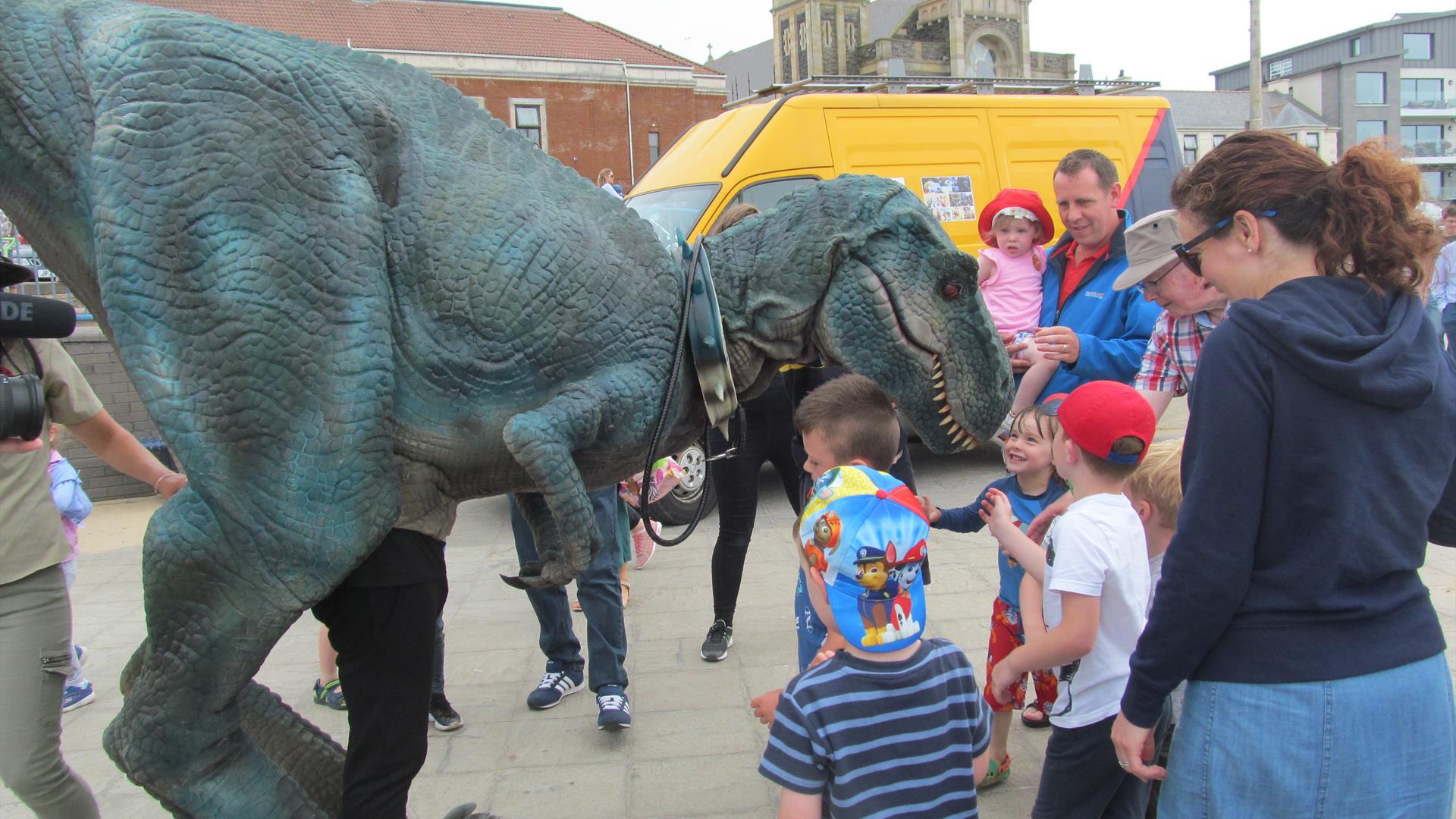 Image shows a large mechanical dinosaur with a group of children standing round it.