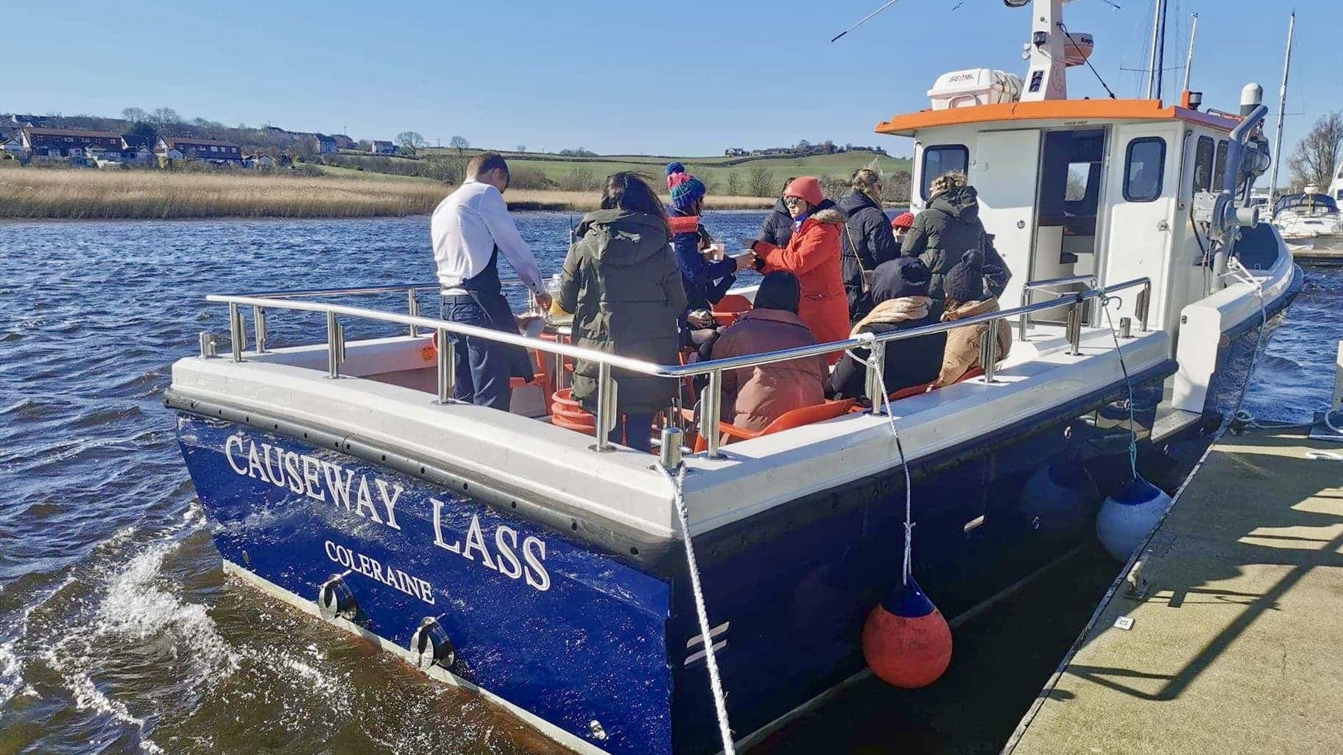 people on a boat docked at a harbour. signage on the boat reads 'Causeway Lass Coleraine' people on a boat docked at a harbour. signage on the boat reads 'Causeway Lass Coleraine'