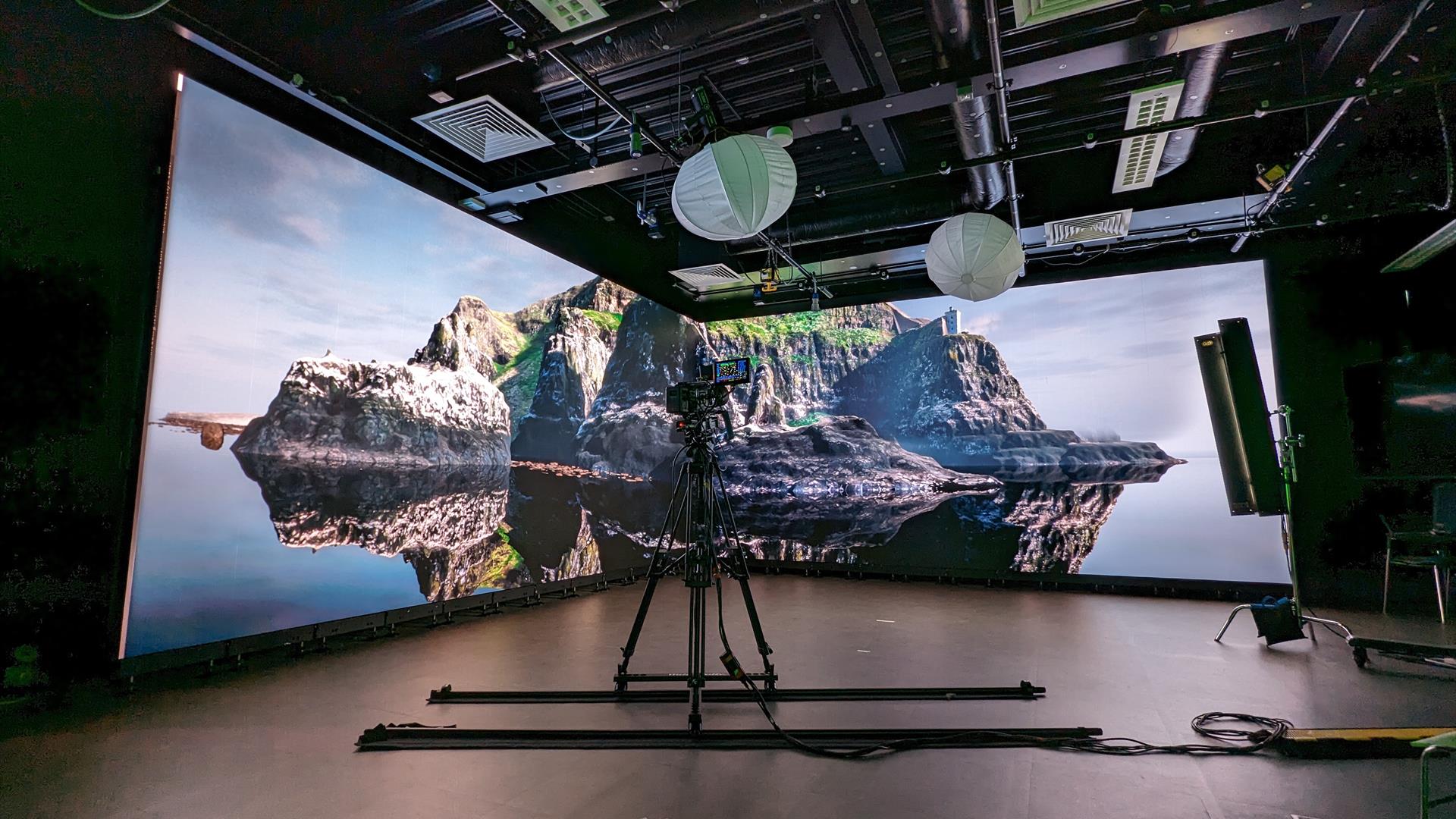 a camera is placed in front of a large double digital screen projecting an image of Rathlin Island