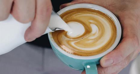 milk being poured in to coffee
