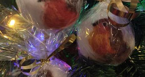 Image shows a needle felted robin decoration hanging on a Christmas tree