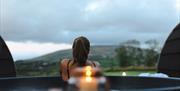 a shoulders and head back view of a person in hot tub looking out onto the mountain and landscape.