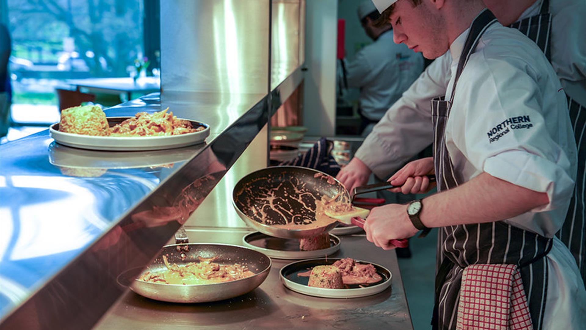 a chef works at a serving station with a frying pan a chef works at a serving station with a frying pan