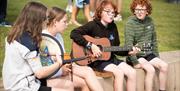 Four children playing traditional Irish music on the green