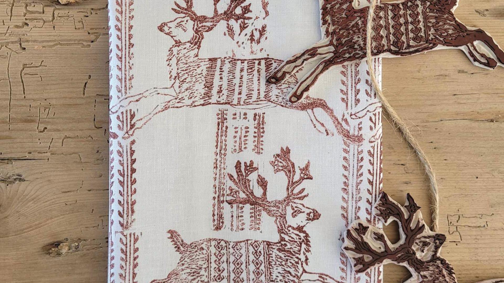 A piece of linen sitting on a wooden surface has been printed with ink using deer-shaped printing blocks on a string A piece of linen sitting on a wooden surface has been printed with ink using deer-shaped printing blocks on a string