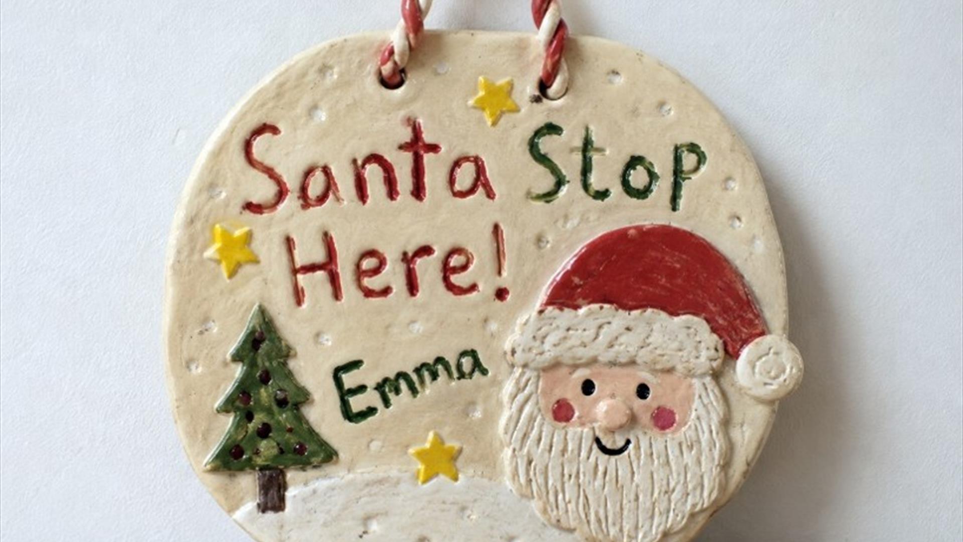 a clay sign that says santa stop here with a picture of santa on it. a clay sign that says santa stop here with a picture of santa on it.