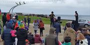 Two performers on stilts and wearing black bowler hats entertaining the crowd in Ballycastle