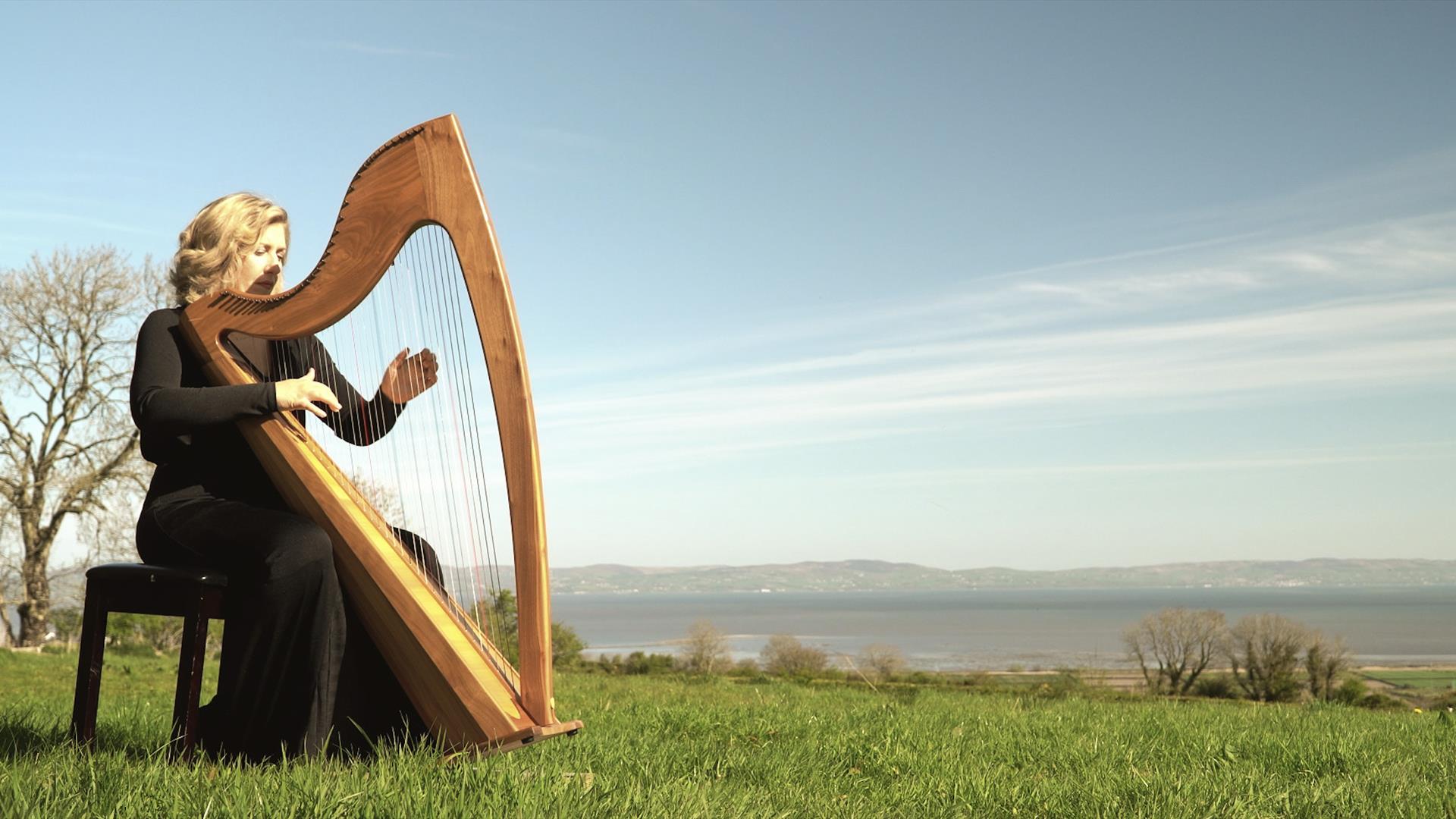 lucia mcginnis plays the irish harp outside with Lough Foyle in the background lucia mcginnis plays the irish harp outside with Lough Foyle in the background