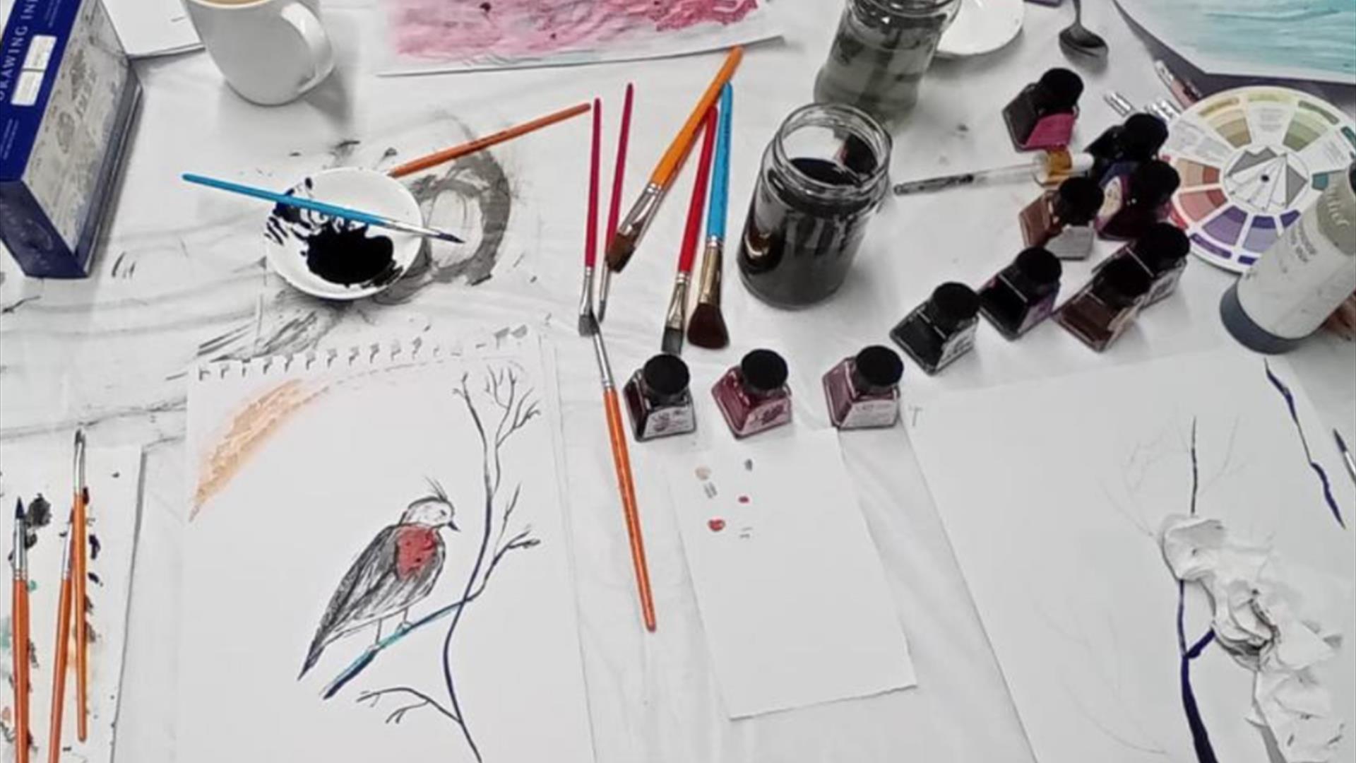 a variety of brushes and inkpots next to a painting of a small bird on a branch a variety of brushes and inkpots next to a painting of a small bird on a branch