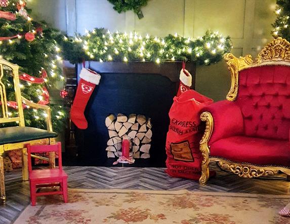 Santa's Grotto with a twinkling Christmas tree, large gold chair and a red letter sack