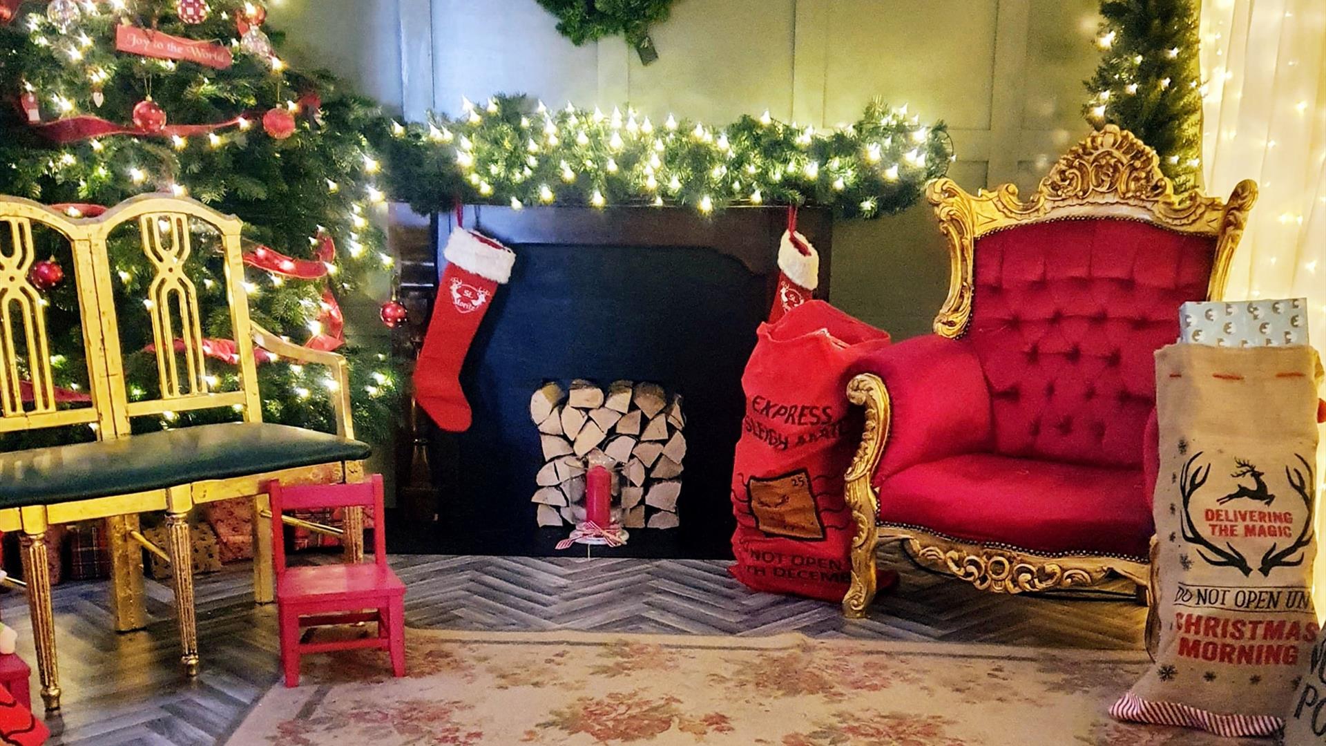 Santa's Grotto with a twinkling Christmas tree, large gold chair and a red letter sack