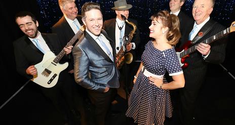 Image shows a band in 50's style dress and musical instruments