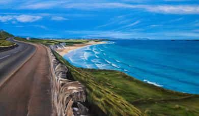 painting of a coastal road looking down on to a beach and the sea on a b right sunny day. 