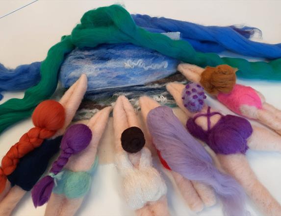 image of 6 differently designed needle felted sea swimmers in different colours such as lilac, pink, and turquoise, all pointing towards a needled fel