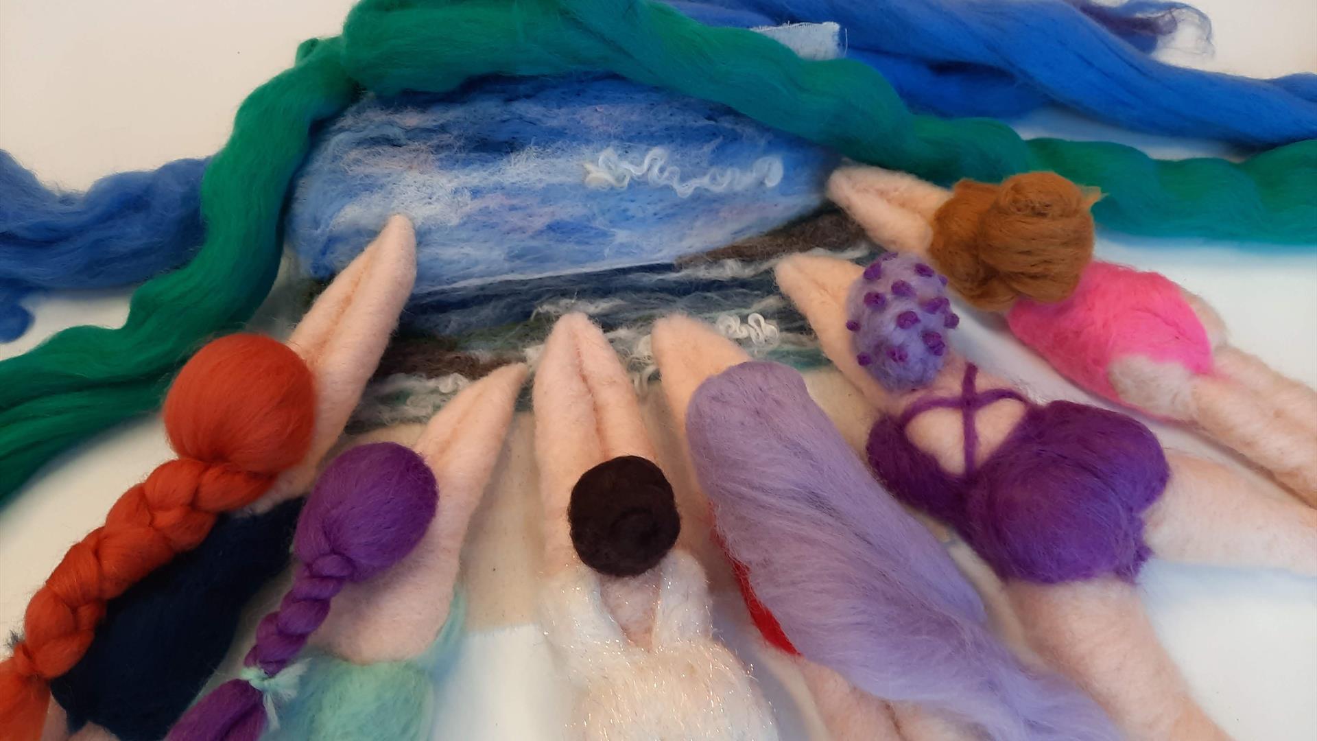 image of 6 differently designed needle felted sea swimmers in different colours such as lilac, pink, and turquoise, all pointing towards a needled fel