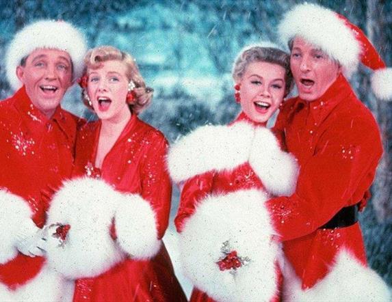 Two men  and two  women dressed festively singing Christmas carols