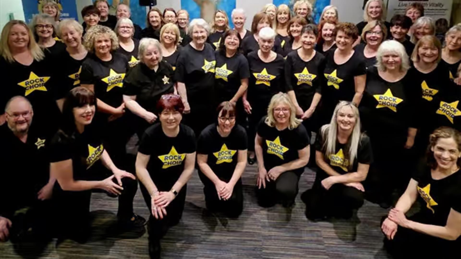 Members of the NI Rock Choir kneeling for a photo Members of the NI Rock Choir kneeling for a photo