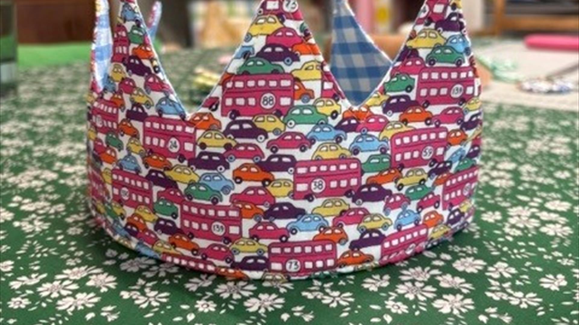 image of a fabric birthday criwn witha bus and car print. image of a fabric birthday criwn witha bus and car print.