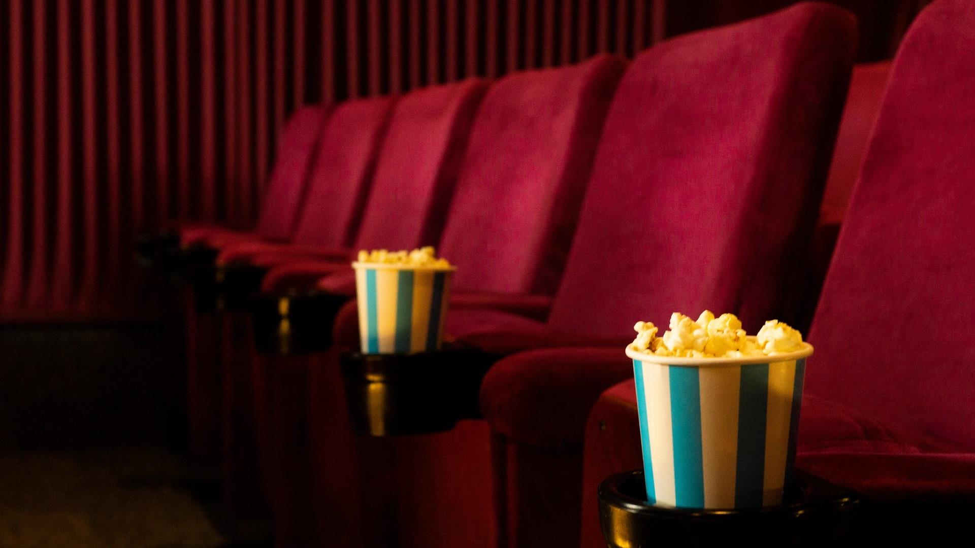 red cinema chairs with buckets of popcorn in the arm rest holder