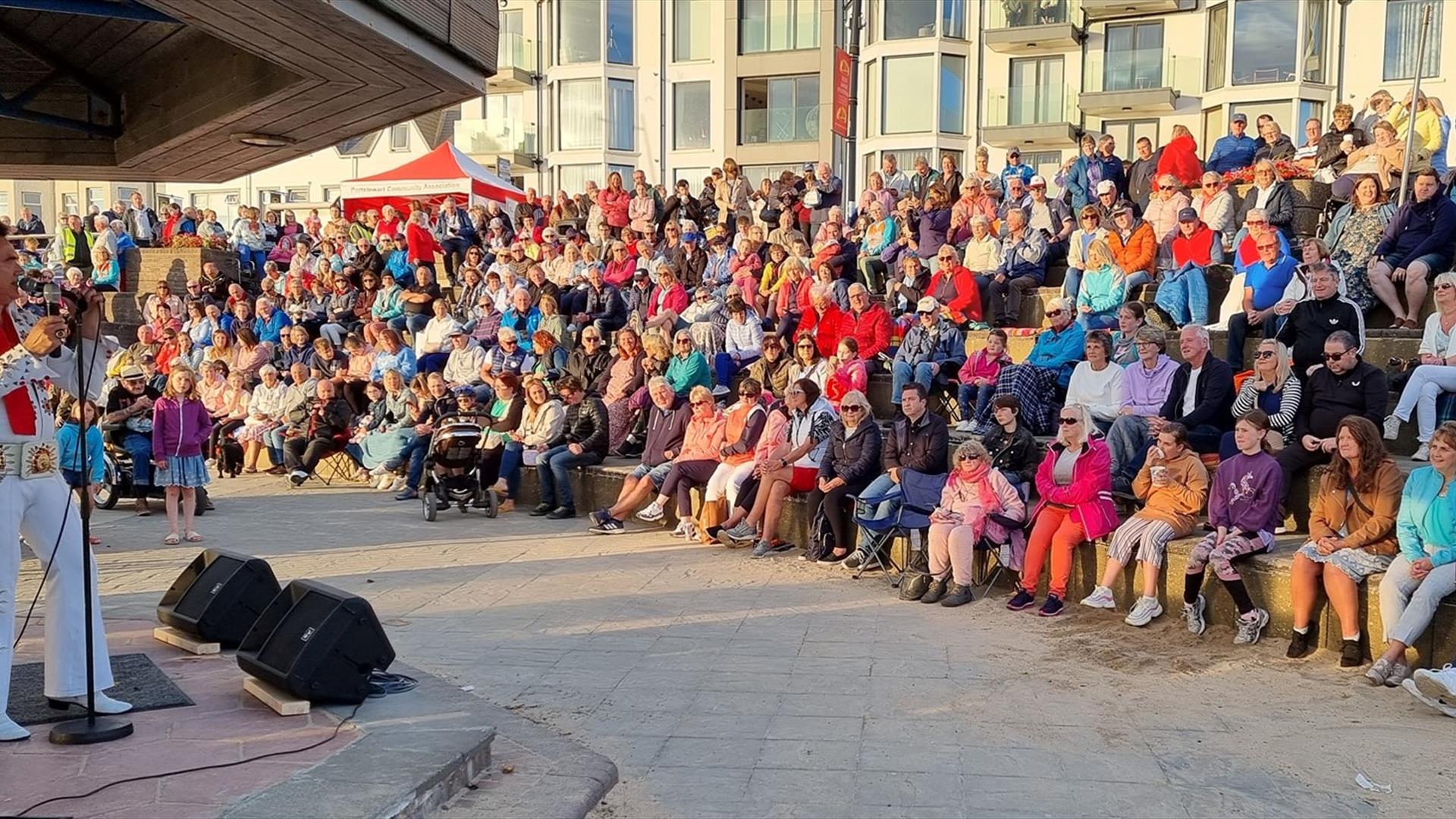Elvis Show at Red Sails Festival with a full crowd sitting in front of him
