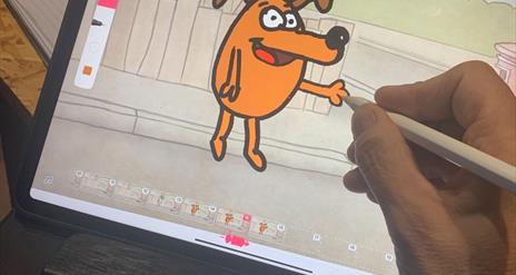 Image shows a hand drawing a cartoon dog on a computer screen