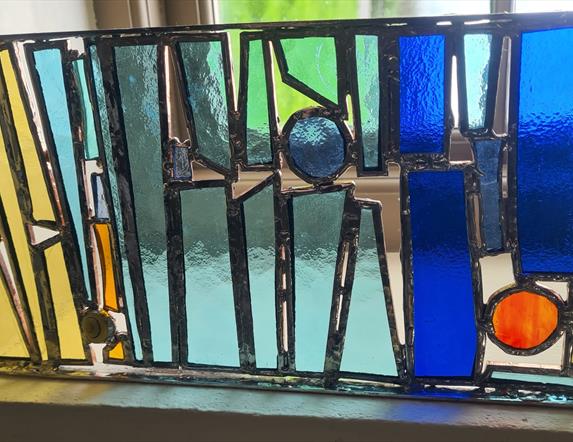 A stained glass Tiffany panel painted in blue, green and yellow colours