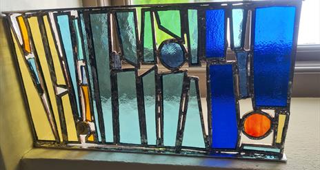 A stained glass Tiffany panel painted in blue, green and yellow colours
