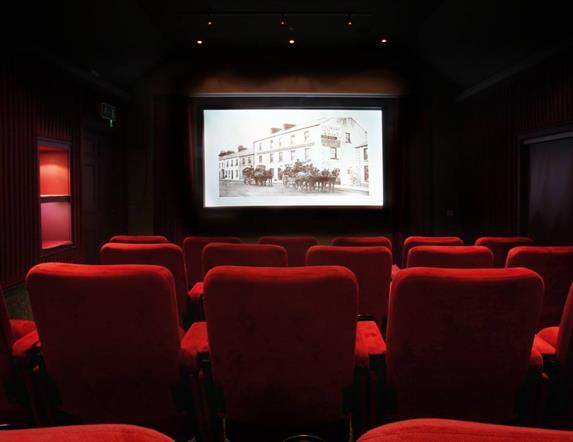 The Bushmills Inn Still Room Cinema with red chairs and a screen at the front