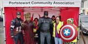 Superheroes Captain America, Groot and Batman with volunteers inside a red gazebo