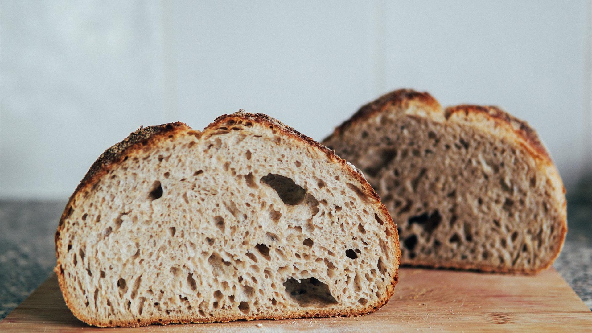 a sour dough loaf split in half rests on a wooden chopping board a sour dough loaf split in half rests on a wooden chopping board