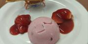 a pink coloured sorbet with strawberries in a red coulis