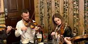 a group of people playing violins around a table of drinks