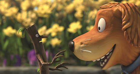 CGI image of a stick that looks like a man standing in front of an orange dog.  the stickman looks scared the dog looks happy.